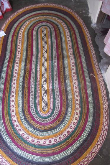 A colourful oval plaited rug in bright stripes
